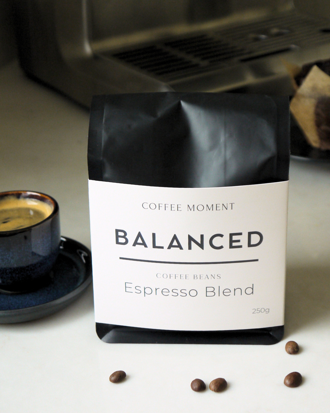 Coffee beans package labeled 'Balanced Espresso Blend' on a light surface with coffee beans around.