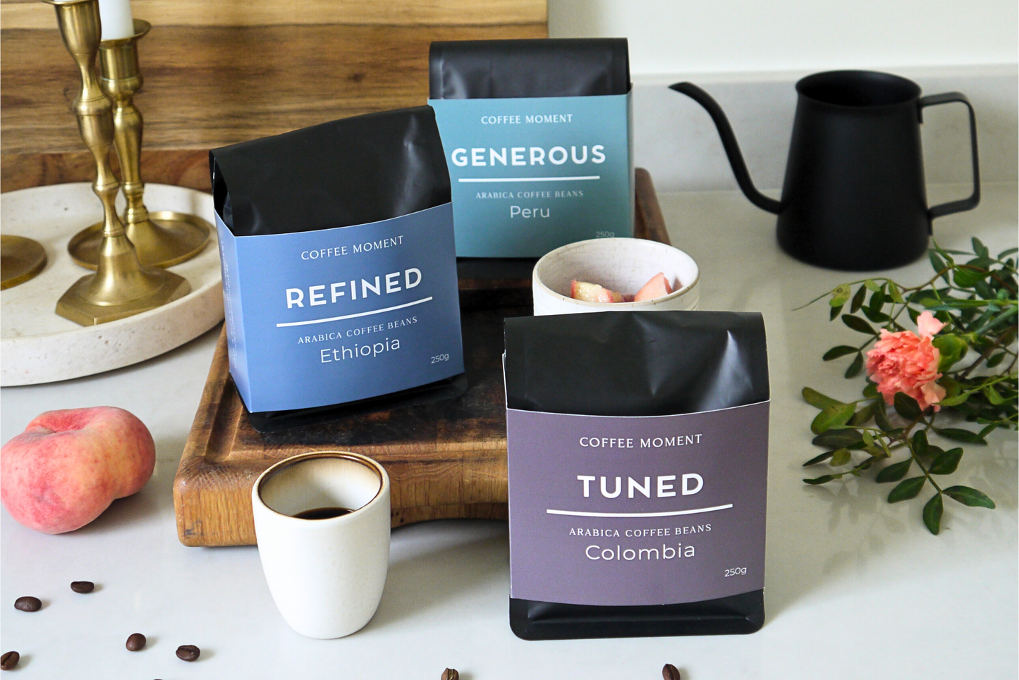 Coffee bags labeled 'Refined', 'Generous', and 'Tuned' on a table with coffee and decor.