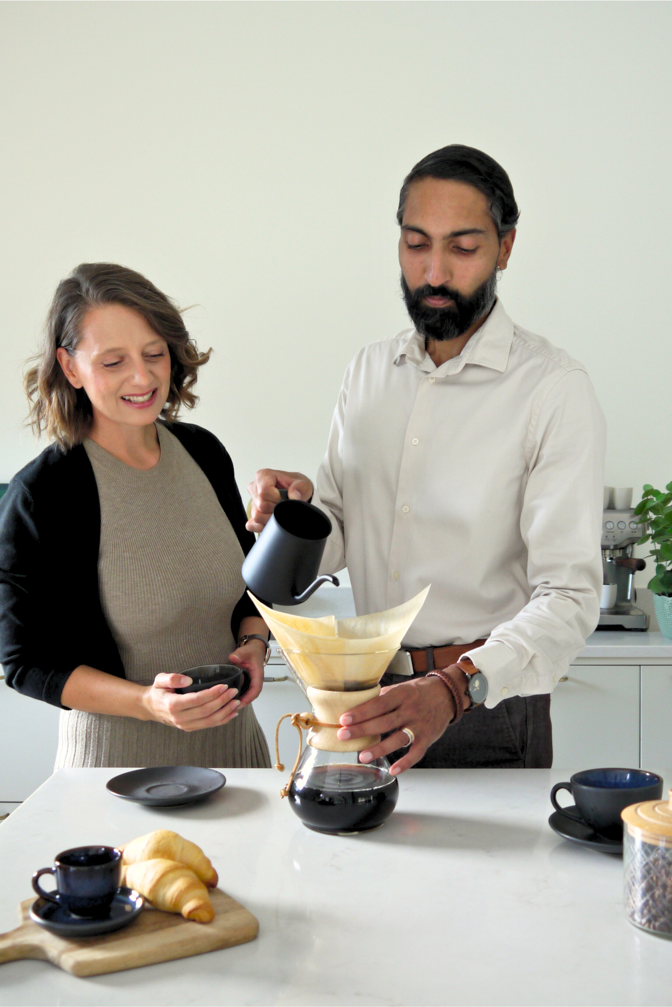 Malin and Rashma Randeniye, owners of Coffee Moment making coffee using a pour-over method in a kitchen.