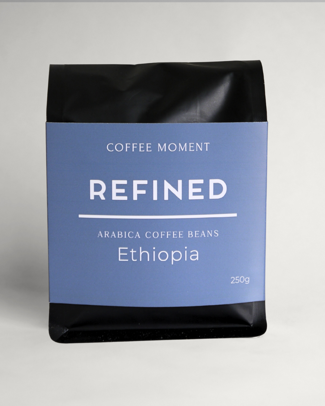 Coffee beans package labeled 'Refined Ethiopia' by 'Coffee Moment' on a gray background